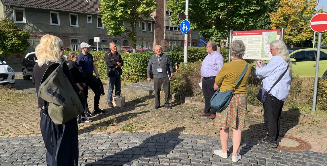 Eine Gruppe Menschen steht im Kreis auf einem Parkplatz