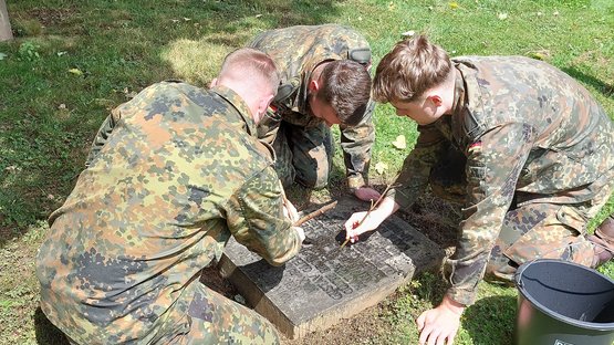 Soldaten reinigen ein Kriegsgrab auf dem Kasseler Hauptfriedhof