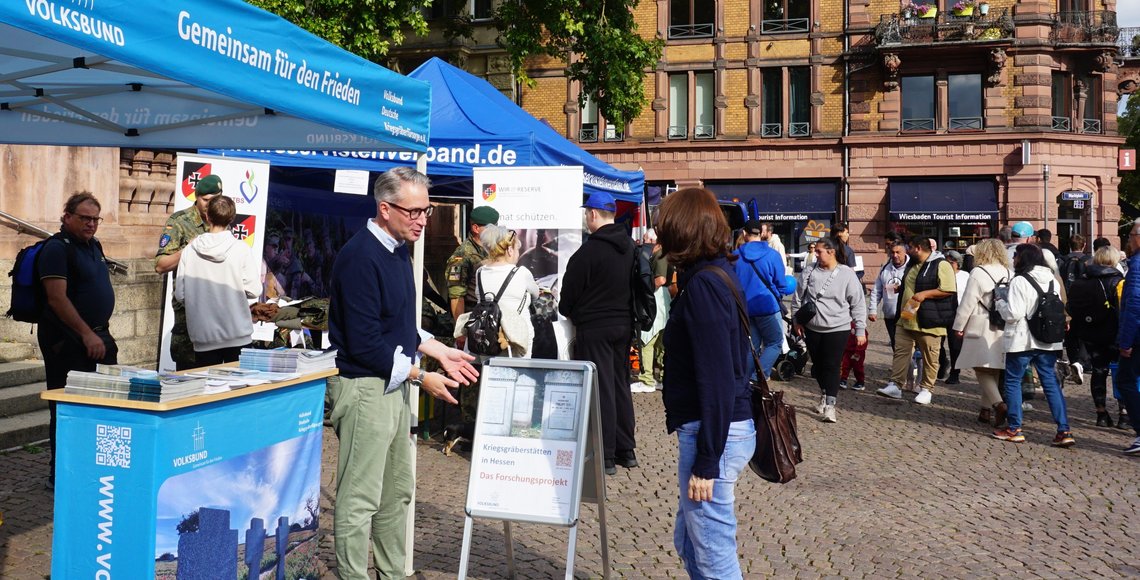 Volksbund-Mitarbeiter und Besucherin am Infostand des Landesverbands Hessen