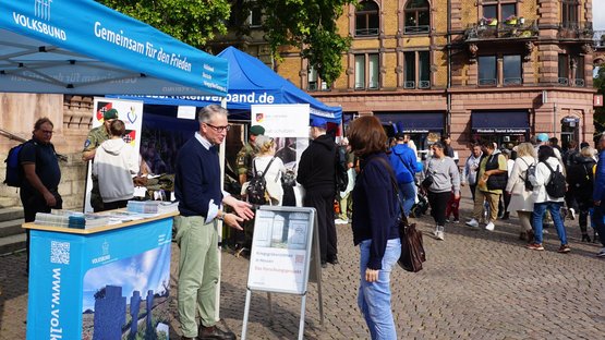 Volksbund-Mitarbeiter und Besucherin am Infostand des Landesverbands Hessen