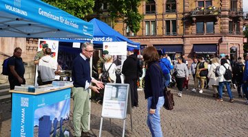 Volksbund-Mitarbeiter und Besucherin am Infostand des Landesverbands Hessen